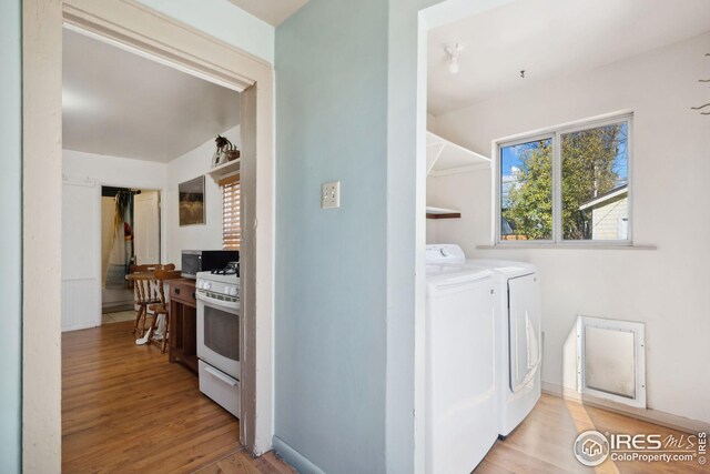 clothes washing area with washing machine and clothes dryer and light hardwood / wood-style floors