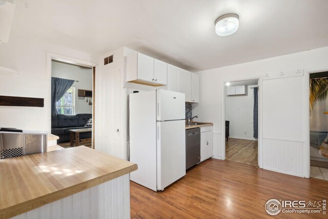 kitchen featuring white cabinets, sink, stainless steel dishwasher, white fridge, and light wood-type flooring