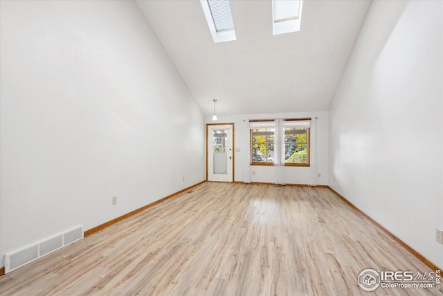 empty room with light wood-type flooring, a skylight, visible vents, and high vaulted ceiling