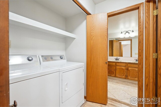 washroom featuring a sink, laundry area, light tile patterned floors, and washer and dryer