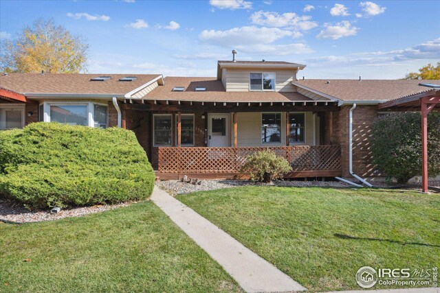 view of front facade with roof with shingles, a front lawn, and brick siding