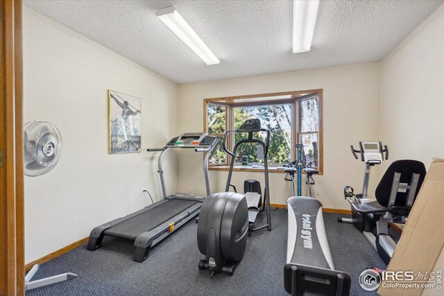 exercise room with a textured ceiling and baseboards