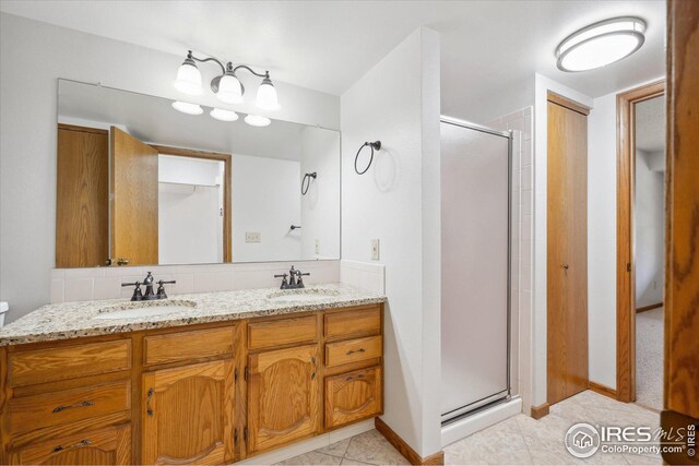 full bathroom with double vanity, a stall shower, tile patterned flooring, and a sink