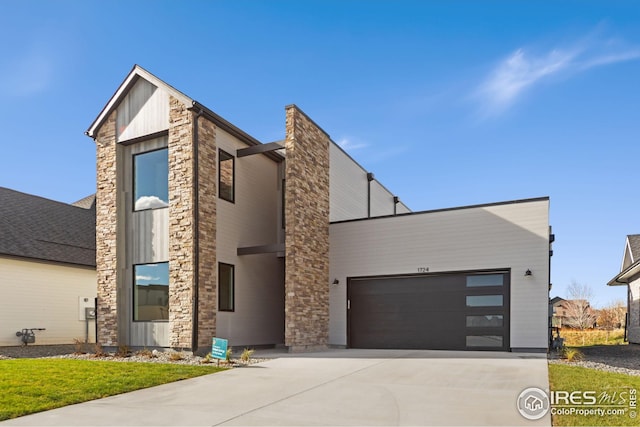 view of front of home with stone siding, board and batten siding, driveway, and a garage