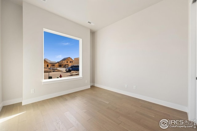 unfurnished room featuring visible vents, baseboards, and wood finished floors