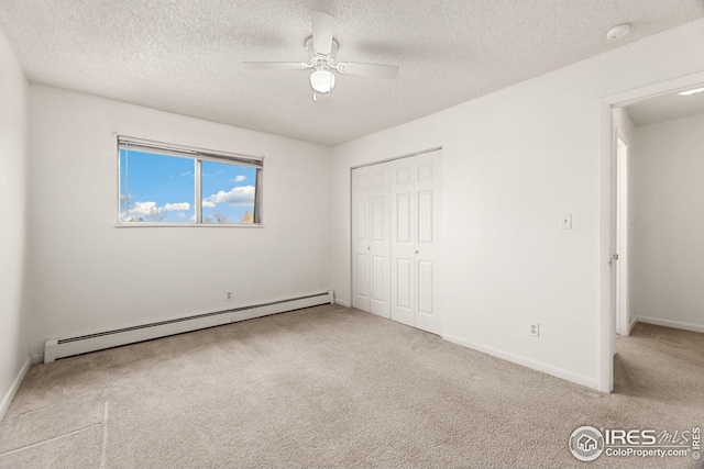 unfurnished bedroom featuring a baseboard heating unit, a textured ceiling, ceiling fan, and a closet