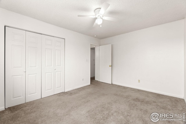 unfurnished bedroom with a closet, a textured ceiling, light colored carpet, and ceiling fan