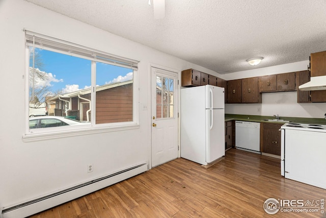 kitchen with a textured ceiling, sink, a baseboard heating unit, white appliances, and light hardwood / wood-style flooring