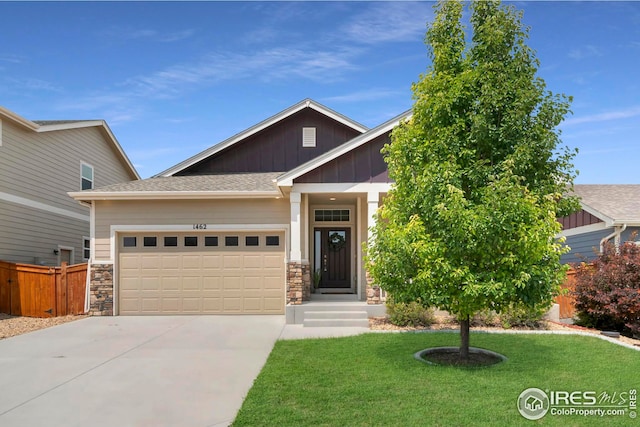 view of front of house featuring an attached garage, board and batten siding, a front yard, stone siding, and driveway