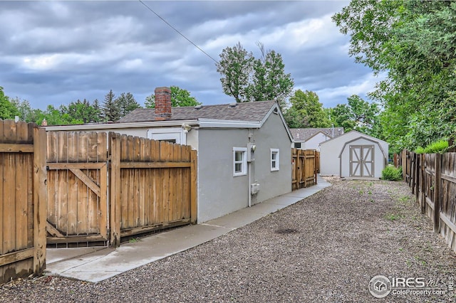 1127 W Mulberry St, Fort Collins, CO 80521 - view of side of home featuring roof with shingles, stucco siding, a gate, a fenced backyard, and a chimney