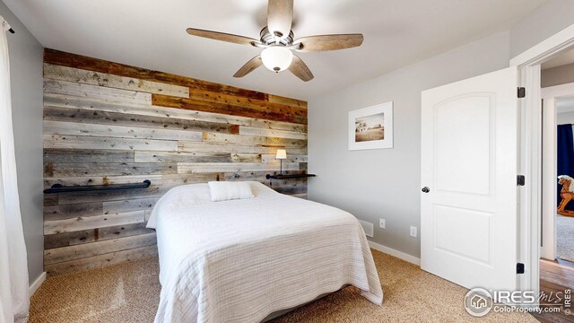 carpeted bedroom with wood walls and ceiling fan