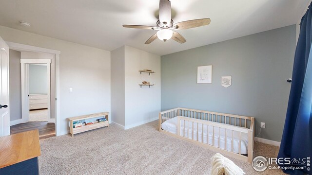 carpeted bedroom with a nursery area and ceiling fan