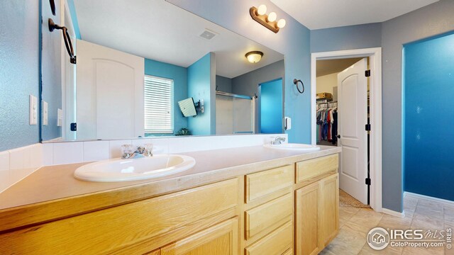 bathroom with tile patterned floors, vanity, and a shower with door