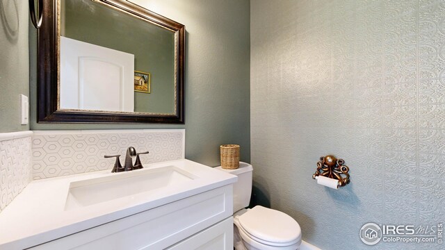 bathroom featuring vanity, toilet, and tasteful backsplash