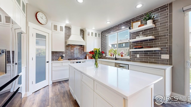 kitchen with white cabinets, dark hardwood / wood-style floors, custom exhaust hood, and a center island