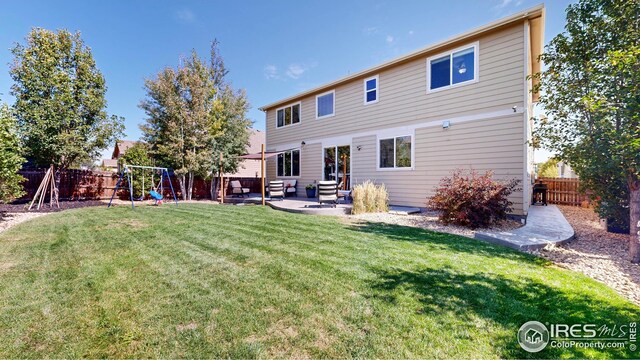 back of house with a playground, a yard, and a patio area