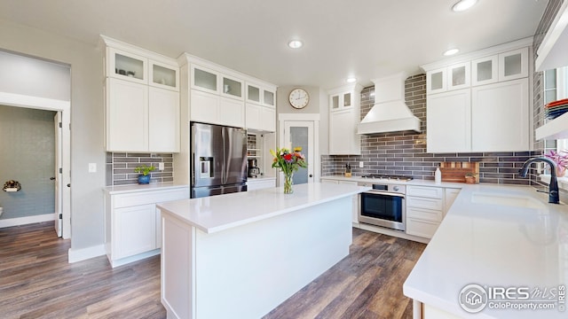 kitchen featuring stainless steel appliances, custom range hood, a kitchen island, white cabinets, and dark hardwood / wood-style flooring