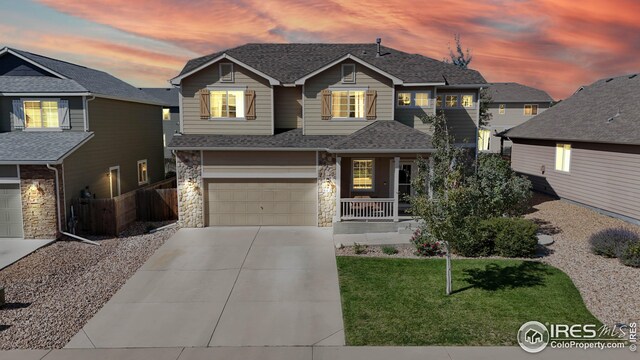 view of front facade featuring a garage, a lawn, and covered porch