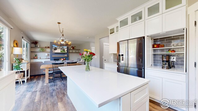 kitchen with light hardwood / wood-style flooring, a kitchen island, stainless steel fridge, and white cabinets