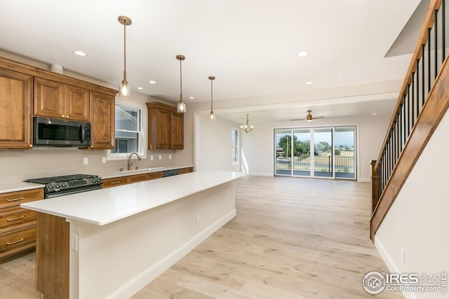 kitchen with stainless steel appliances, a sink, backsplash, brown cabinets, and light wood finished floors