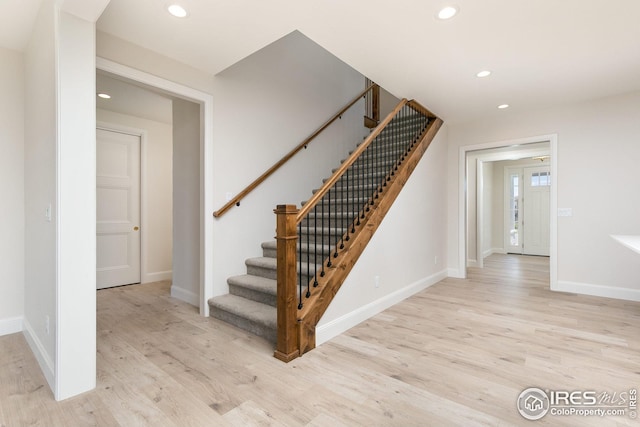 stairs featuring baseboards, wood finished floors, and recessed lighting