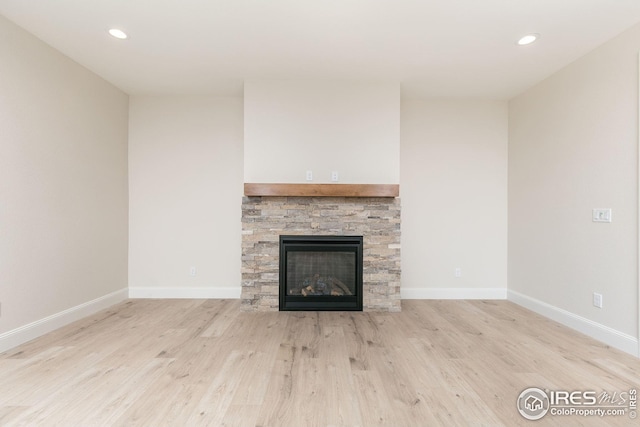 unfurnished living room with recessed lighting, baseboards, wood finished floors, and a stone fireplace