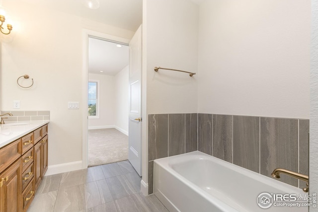 bathroom with a garden tub, baseboards, and vanity