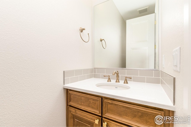 bathroom featuring visible vents, backsplash, and vanity