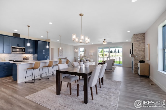 dining space with baseboards, ceiling fan with notable chandelier, light wood-style flooring, and recessed lighting