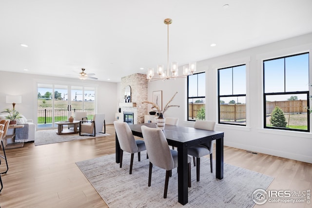 dining space with light wood-type flooring, visible vents, a stone fireplace, and recessed lighting