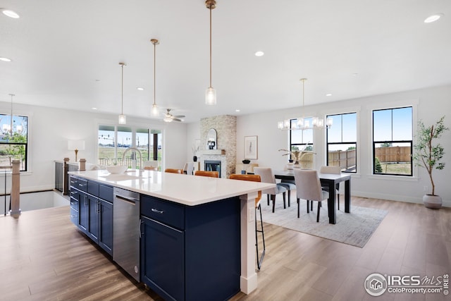 kitchen with blue cabinets, a wealth of natural light, a fireplace, and light wood finished floors