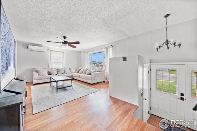 living room featuring light wood-type flooring, a textured ceiling, and a wealth of natural light