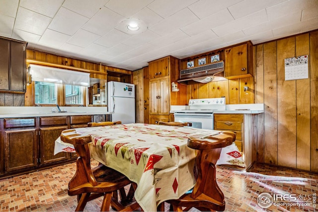 kitchen featuring wooden walls, white appliances, sink, and extractor fan