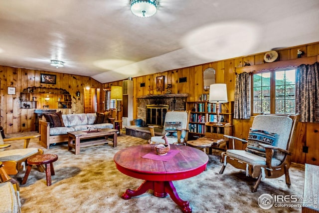 carpeted living room with vaulted ceiling, a stone fireplace, and wood walls