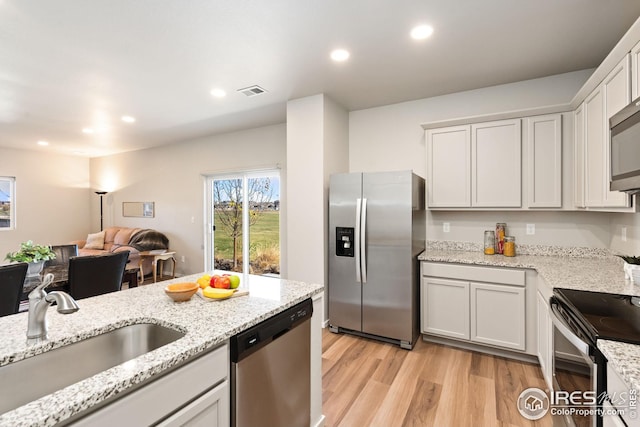 kitchen featuring white cabinets, sink, light hardwood / wood-style floors, light stone counters, and stainless steel appliances