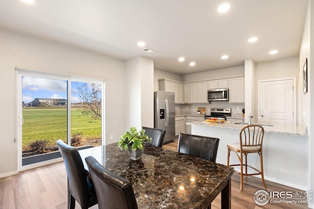 dining room with sink and light hardwood / wood-style flooring