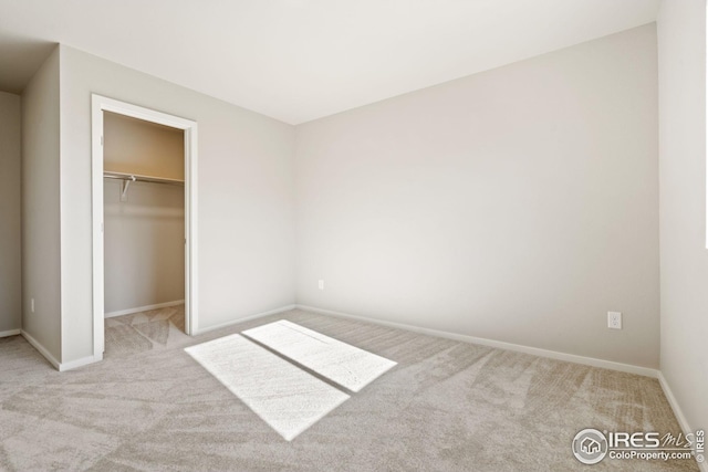 unfurnished bedroom featuring a walk in closet, light carpet, and a closet