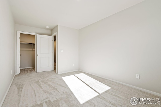 unfurnished bedroom featuring light carpet, a closet, and a spacious closet