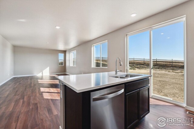 kitchen with hardwood / wood-style floors, stainless steel dishwasher, a kitchen island with sink, and sink