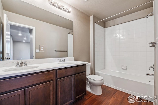 full bathroom with a textured ceiling, toilet, hardwood / wood-style flooring, vanity, and tiled shower / bath