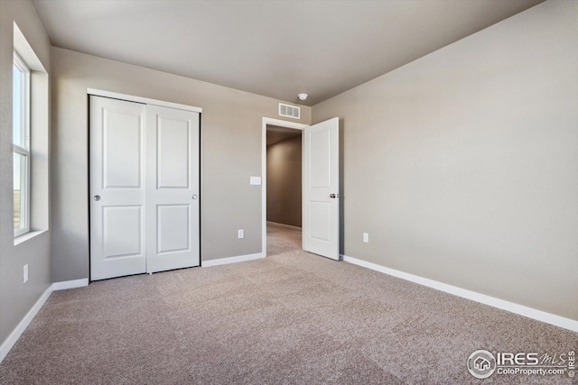 unfurnished bedroom featuring light colored carpet and a closet