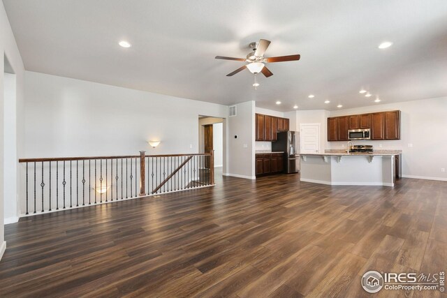 unfurnished living room featuring dark wood-type flooring and ceiling fan