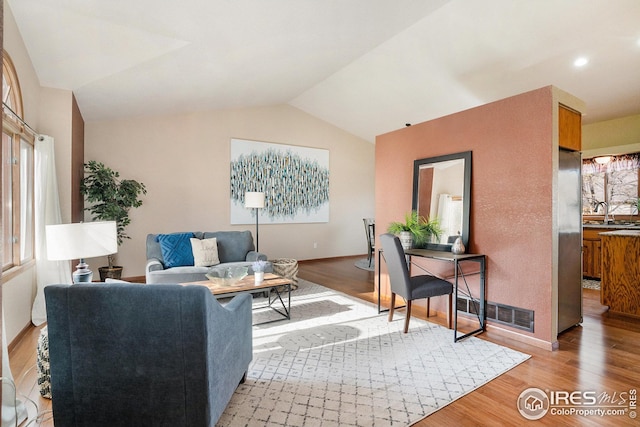 living room featuring light wood-type flooring and vaulted ceiling