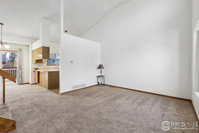 unfurnished living room featuring a chandelier, light colored carpet, a textured ceiling, and vaulted ceiling