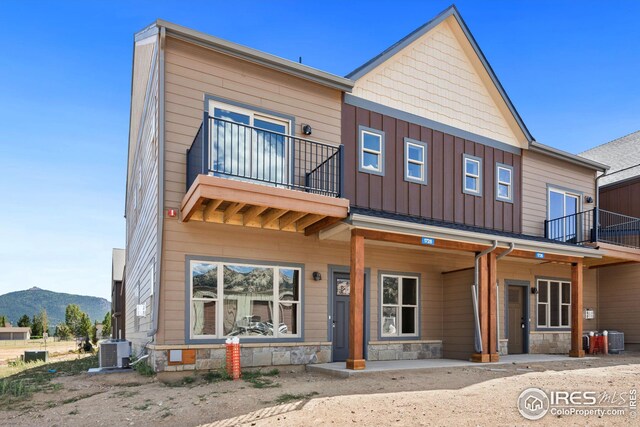 view of front of property featuring a mountain view, a balcony, and central AC