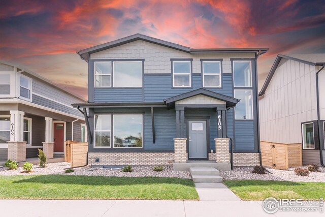 6105 Saddle Horn Dr, Timnath, CO 80547 - view of front of house featuring brick siding, a lawn, and a porch