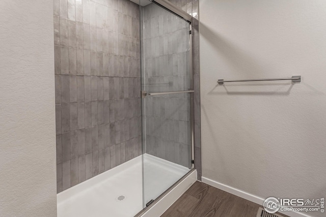 6105 Saddle Horn Dr, Timnath, CO 80547 - full bathroom featuring tiled shower, wood finished floors, baseboards, and a textured wall