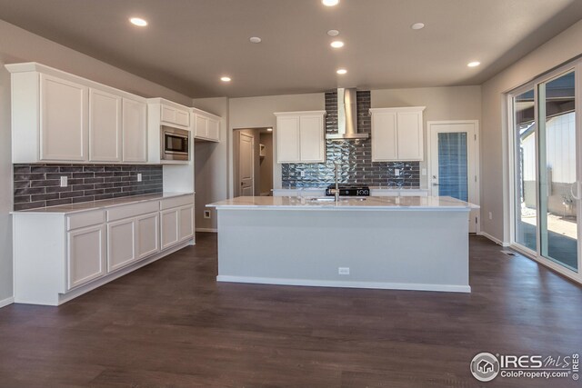 6105 Saddle Horn Dr, Timnath, CO 80547 - kitchen featuring stainless steel microwave, a sink, wall chimney exhaust hood, tasteful backsplash, and white cabinets