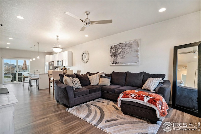 living room with ceiling fan, hardwood / wood-style floors, and a textured ceiling