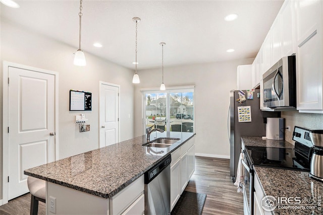 kitchen featuring appliances with stainless steel finishes, sink, a center island with sink, white cabinets, and hanging light fixtures